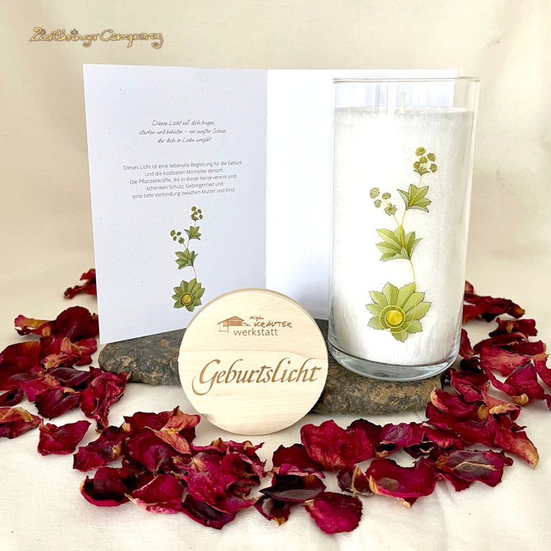 Kerze im Glas der Allgäuer Heilkräutermanufaktur mit einer passend gestalteten Faltkarte präsentiert auf einem Stein mit einem Kranz aus Rosenblüten