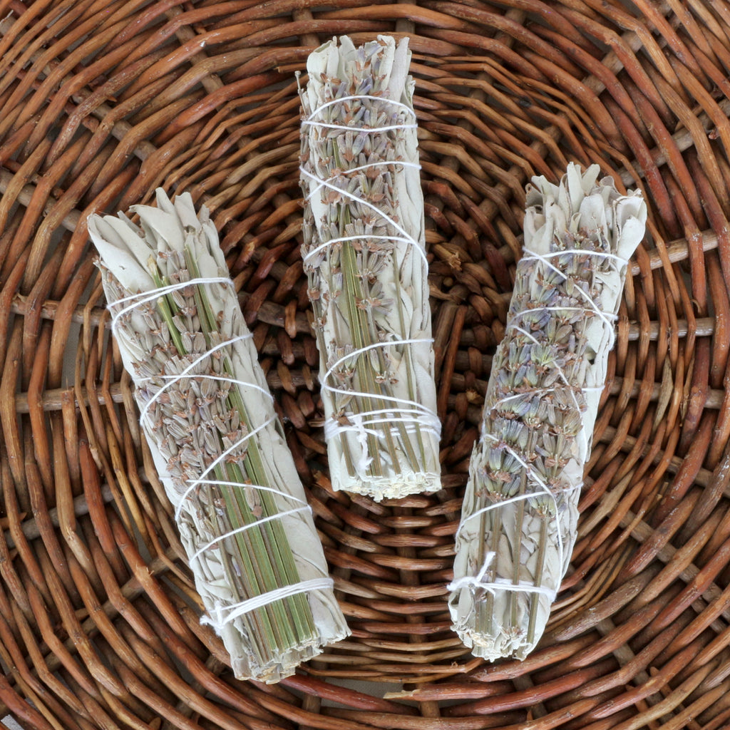 Drei kleine handgebundene Salbei-Lavendel Räucherbündel – Smudge Sticks zur energetischen Reinigung auf einem geflochtenen Weidenteller