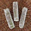 Drei kleine handgebundene Salbei-Lavendel Räucherbündel – Smudge Sticks zur energetischen Reinigung auf einem geflochtenen Weidenteller